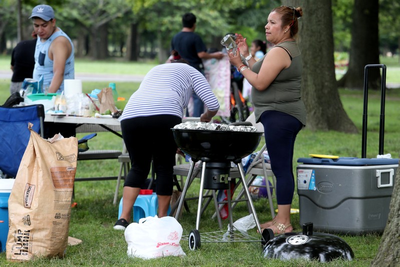 FILE PHOTO: Woman puts corn on the grill at Flushing Meadows Park in the Queens borough of New York City