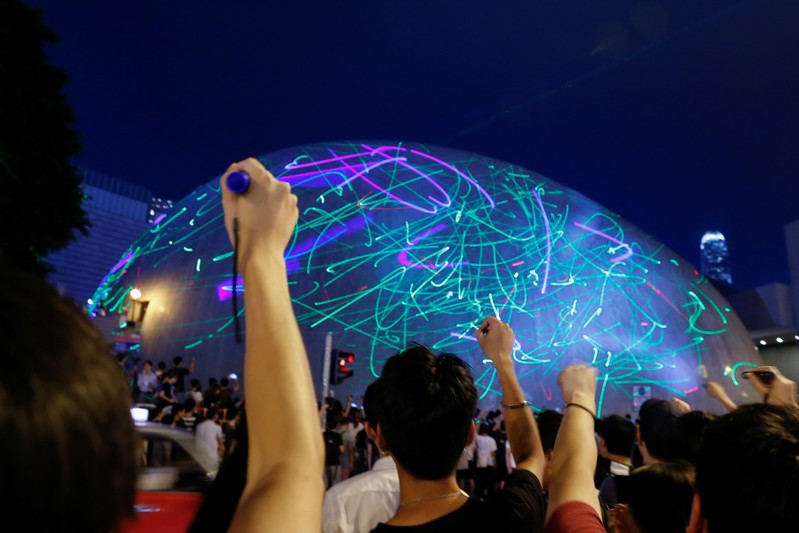 People watch the dots of laser pointers move across the facade of the Hong Kong Space Museum during a flashmob in Hong Kong