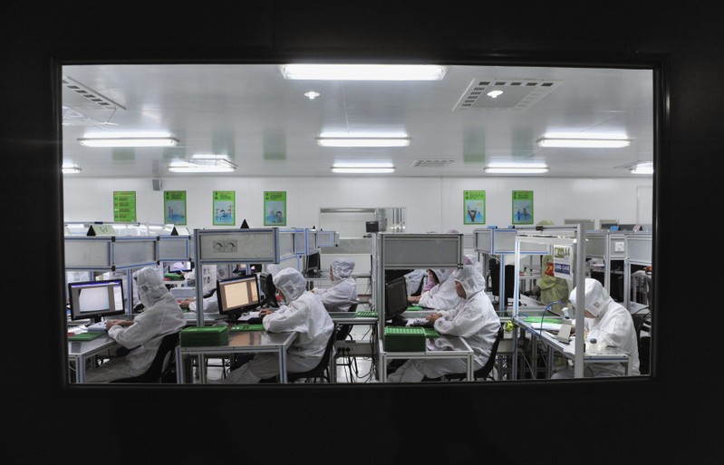 FILE PHOTO: Employees work at a production line inside a factory exporting cameras used in mobile phones, in Shenyang