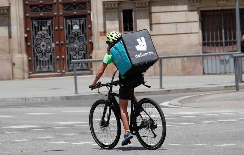 A biker wearing a Deliveroo backpack drives in the central Barcelona