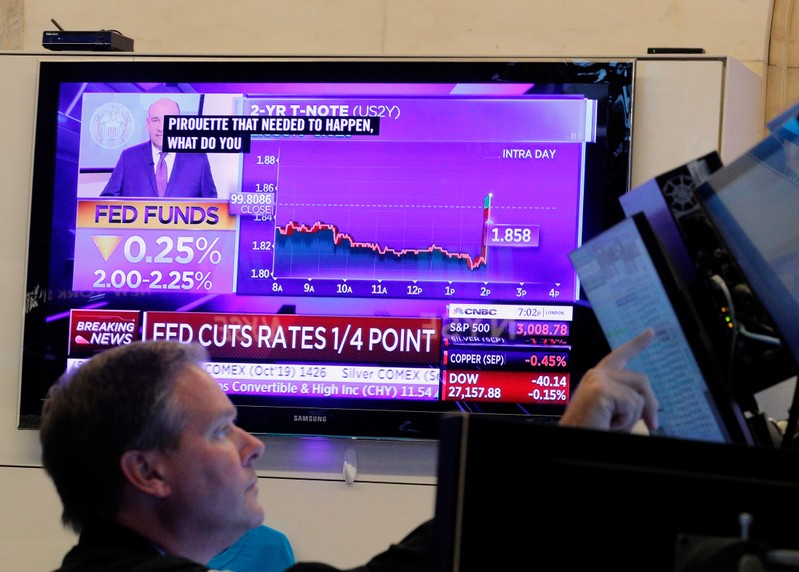 FILE PHOTO: A trader looks on as a screen displays the U.S. Federal Reserve interest rates announcement on the floor of the New York Stock Exchange (NYSE) in New York