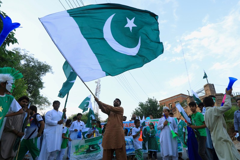 A man from the Pakistan's Hindu community waves national flag with others, during a rally to express solidarity with the people of Kashmir on Pakistan's 72nd Independence Day in Peshawar