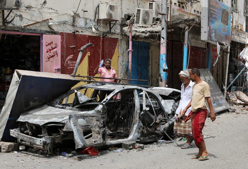FILE PHOTO: People check cars that were burned during clashes in Aden
