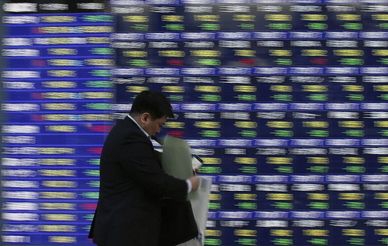 FILE PHOTO: A man walks past a stock quotation board outside a brokerage in Tokyo