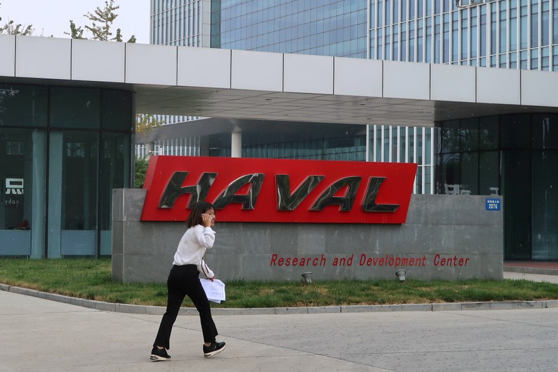 FILE PHOTO: A woman talks on her phone as she walks past a sign of Great Wall’s HAVAL at its research and development center in Baoding, Hebei