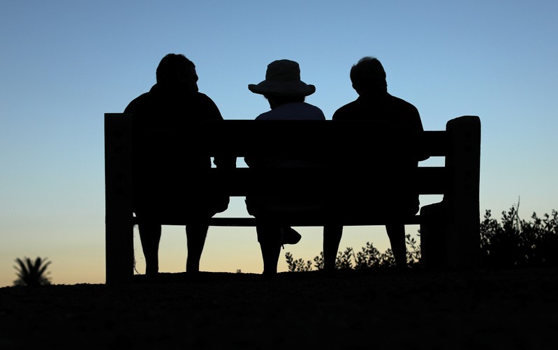 FILE PHOTO: Elderly people sit on a park bench after sun set in Encinitas