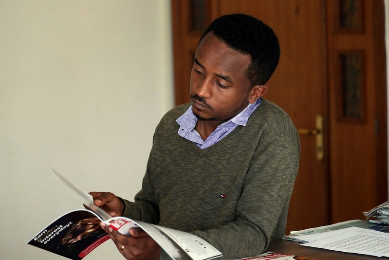 Ethiopian Berhane reads news magazine with cover photo of Ethiopian PM in Addis Ababa