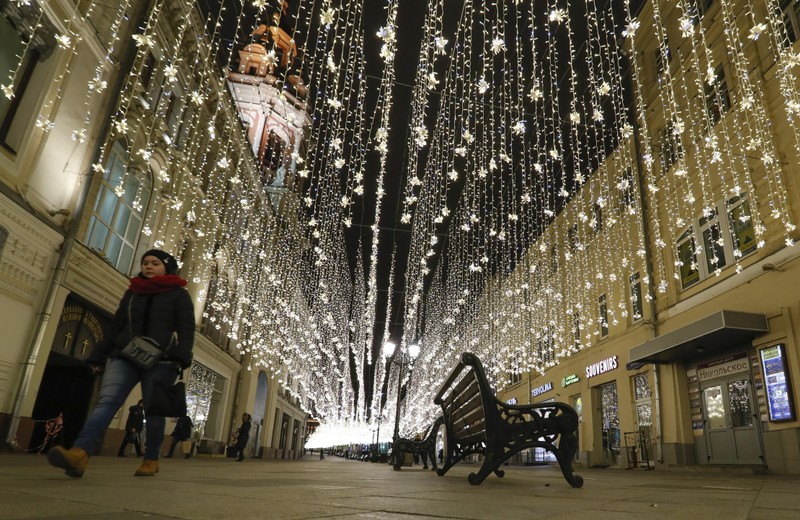 FILE PHOTO: A pedestrian walks along a street, decorated with festive illumination lights prior to the New Year and Christmas holidays, in central Moscow