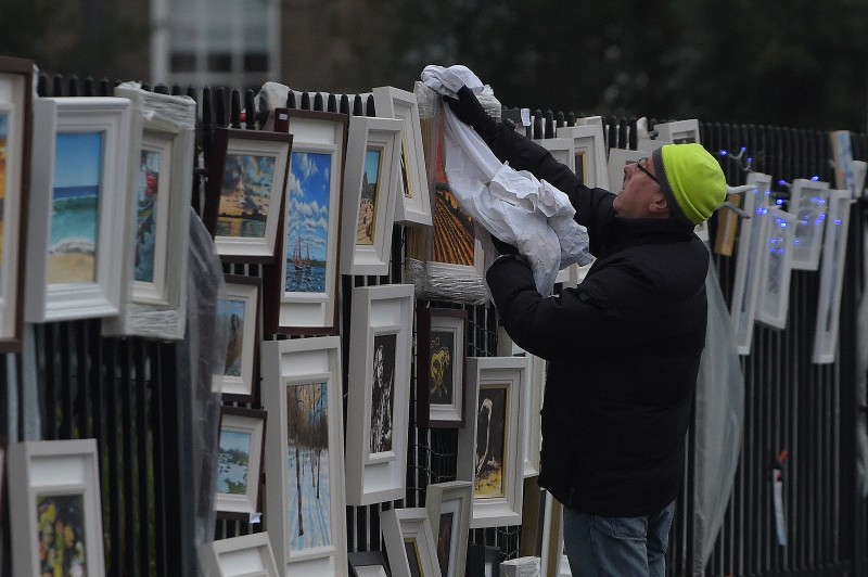 A street vendor dries rain off artworks he is selling on the streets in Dublin