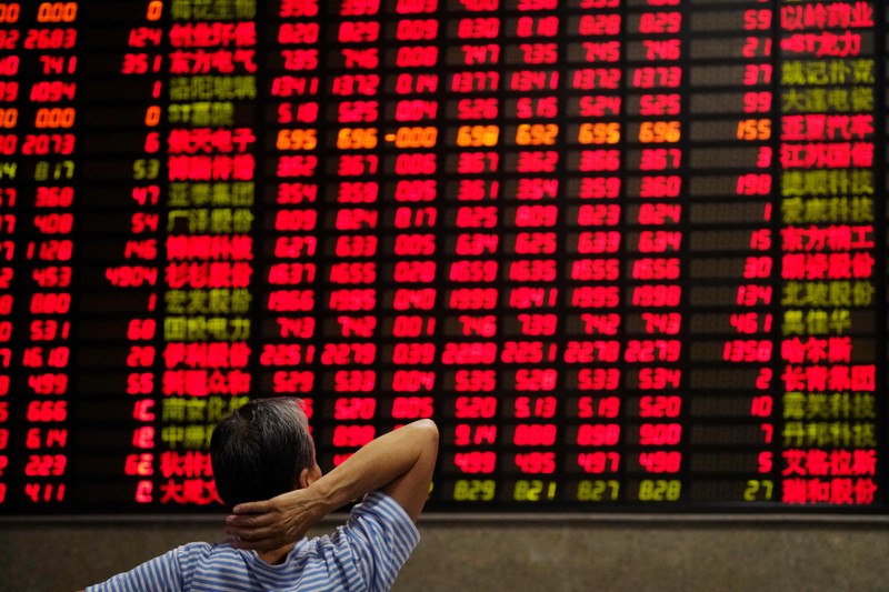 An investor looks at an electronic board showing stock information at a brokerage house in Shanghai