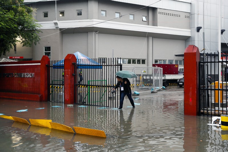 A man walks on the flooded entrance of the Rizal Memorial Stadium after Typhoon Kammuri hit Metro Manila