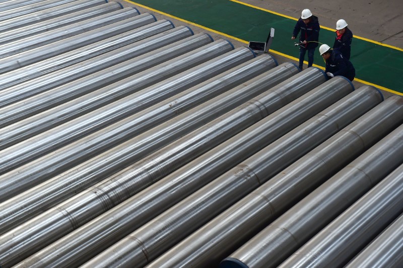 Workers check on seamless steel pipes at a factory of a steel products manufacturer in Cangzhou, Hebei