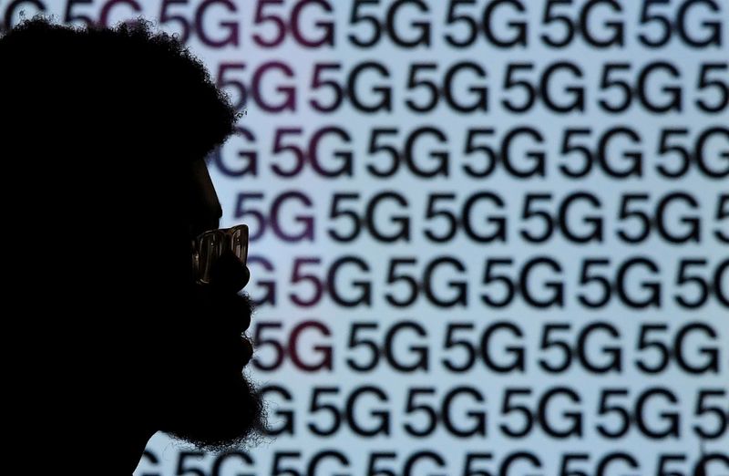 FILE PHOTO: A man walks past an advertisement promoting the 5G data network at a mobile phone store in London