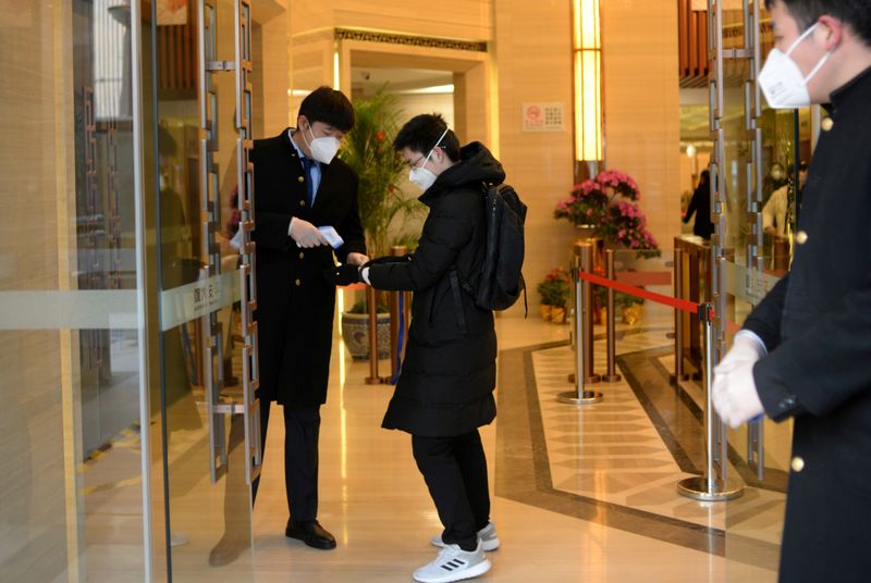 FILE PHOTO: Jin Yang, 28, who works in a department of China's State Administration of Foreign Exchange, has his temperature checked at an entrance to his office, in the morning on his first day of returning to work after the extended Lunar New Year holida