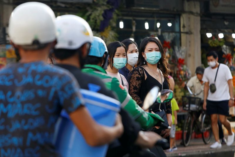 People drive motorbikes near pedestrians wearing face masks in Ho Chi Minh