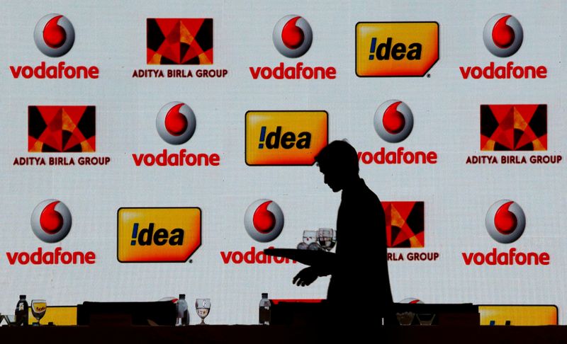 FILE PHOTO: A hotel employee clears a table after Vodafone Group and Idea Cellular news conference in Mumbai