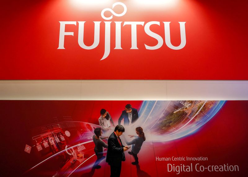 A man looks at his mobile in front of a Fujitsu advert during the Mobile World Congress in Barcelona