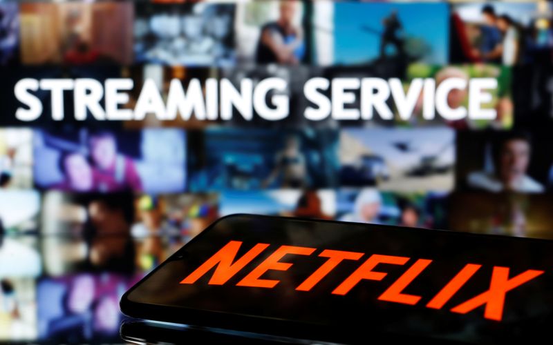 A smartphone with the Netflix logo lies in front of displayed