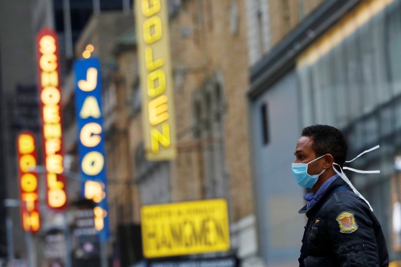 A man in a surgical mask walks through Manhattan's Broadway Theatre district after Broadway shows announced they will cancel performances due to the coronavirus outbreak in Manhattan, New York City