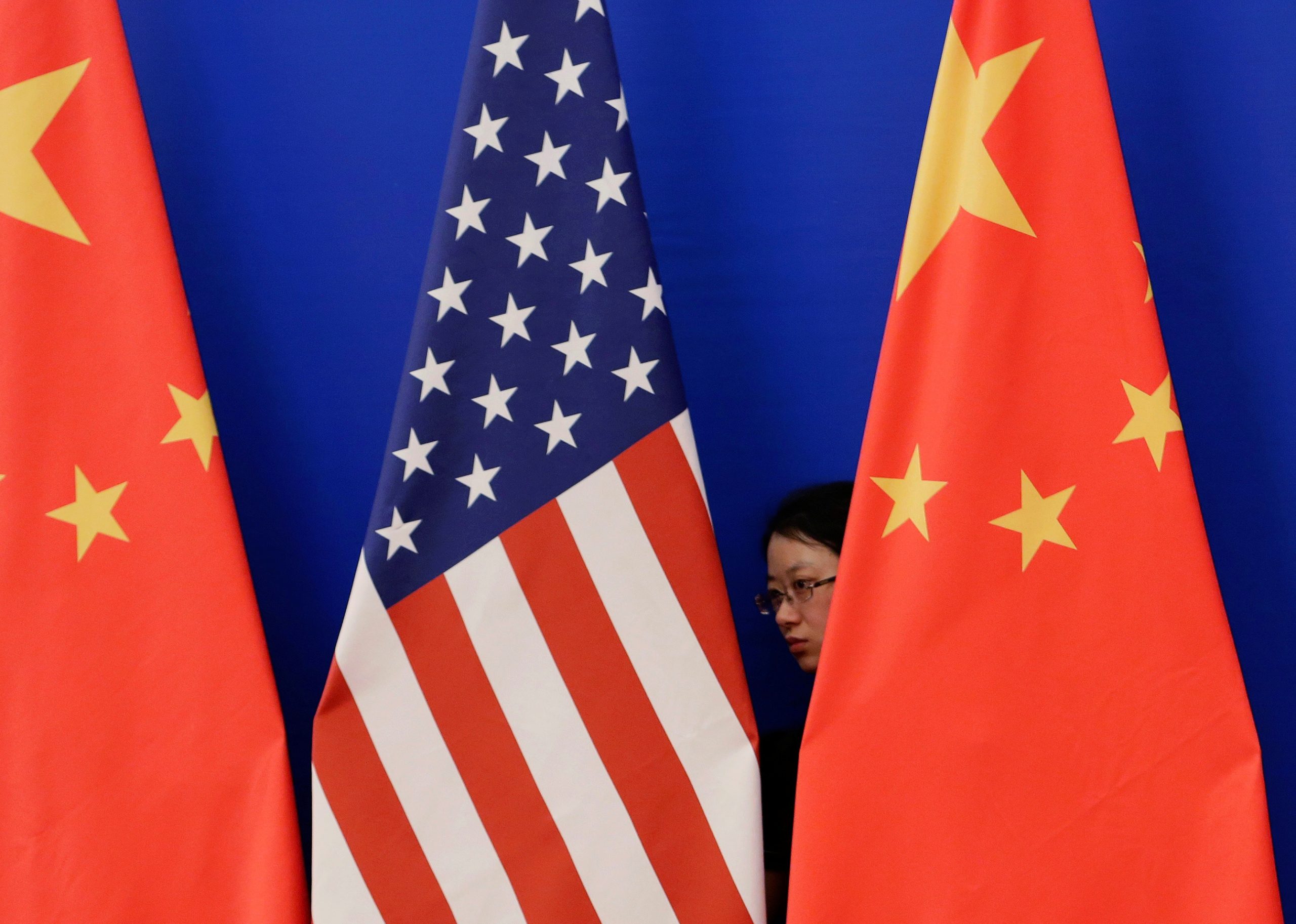 FILE PHOTO: A member of staff from Chinese government adjusts U.S. and Chinese national flags in Beijing