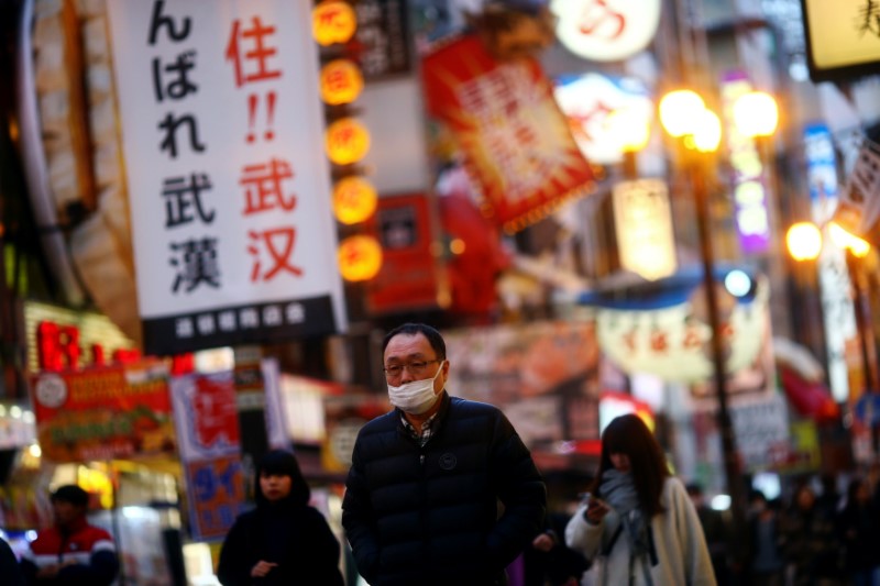 FILE PHOTO: A man, wearing protective mask following an outbreak of the coronavirus disease (COVID-19), walks on an almost empty street in the Dotonbori entertainment district of Osaka