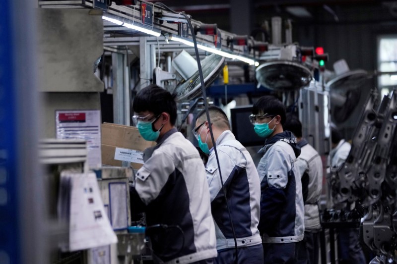 Employees wearing face masks work on a car seat assembly line at Yanfeng Adient factory in Shanghai