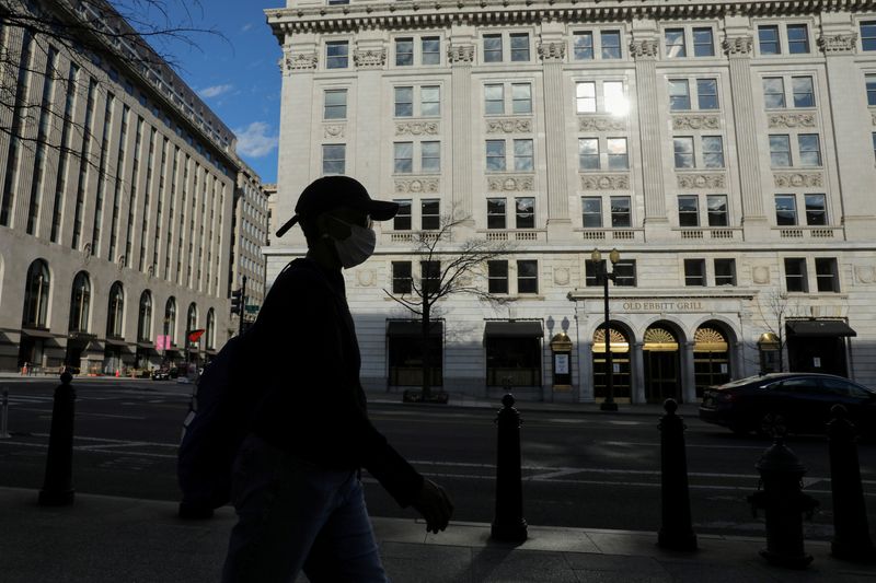 FILE PHOTO: A person in a mask walks on a nearly empty street in the coronavirus outbreak near the Treasury Department in Washington