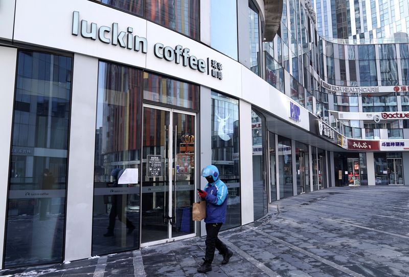 A deliveryman walks past a closed Luckin Coffee store at Sanlitun in Beijing
