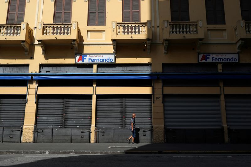 A man wearing protective face mask walks in front of closed stores after the city government decreed the closure of shops and stores as a precautionary measure against coronavirus disease (COVID-19) in downtown Sao Paulo