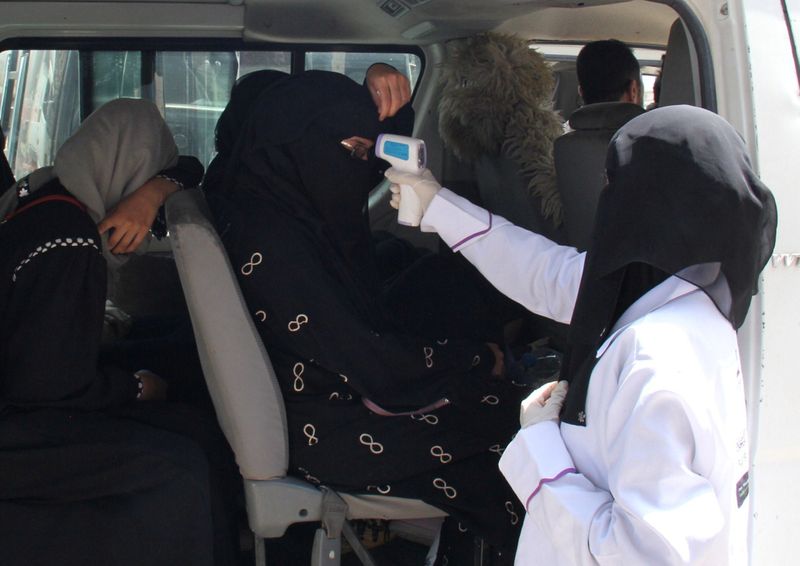 A health worker takes temperature of passengers of a van, amid fear of coronavirus disease (COVID-19), on the outskirts of Taiz