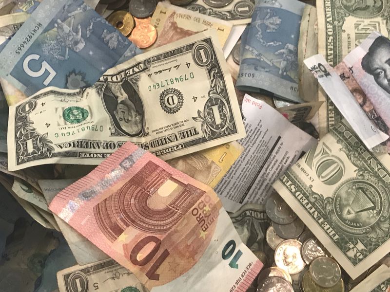 U.S. dollars and other world currencies lie in a charity receptacle at Pearson international airport in Toronto