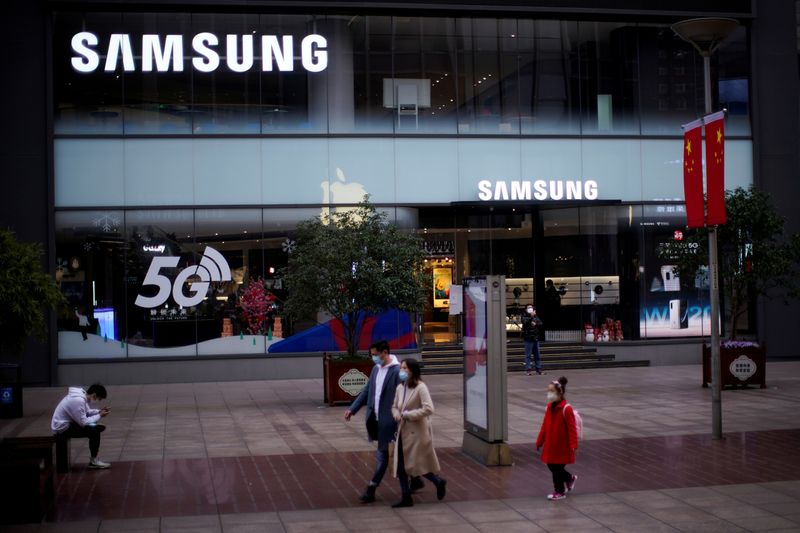 FILE PHOTO: People wears masks in front a Samsung Store at a main shopping area, in downtown Shanghai