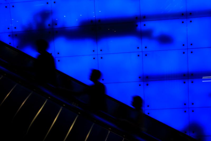 People ride up an escalator at a shopping mall in Singapore