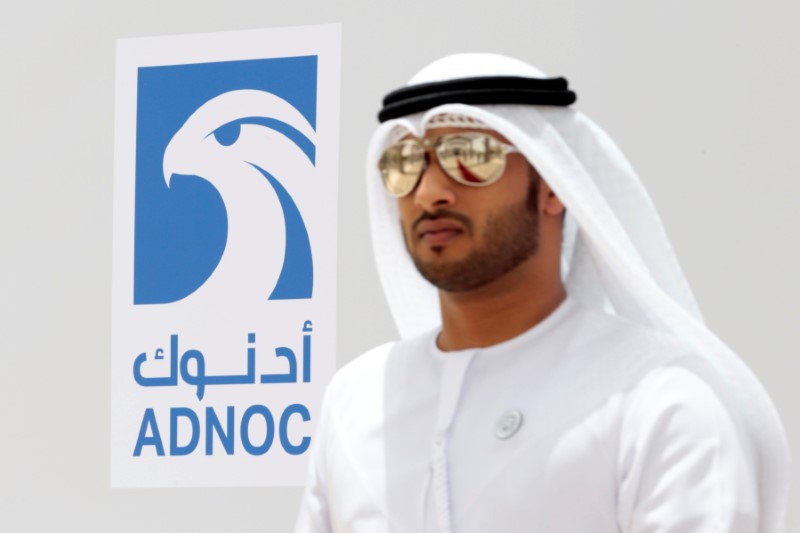 An Emirati man is seen near the logo of ADNOC in Ruwais