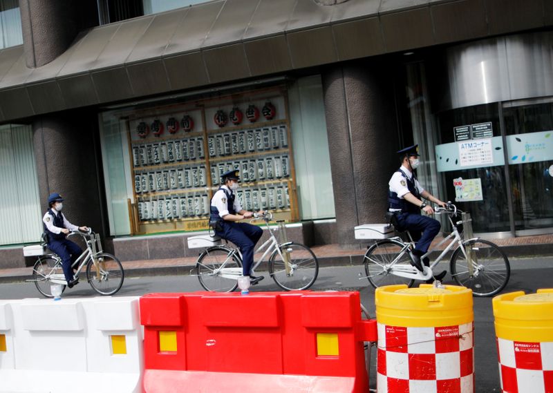 FILE PHOTO: Police officers wearing protective face masks ride bicycles on the street under a nationwide state of emergency as the spread of the coronavirus disease (COVID-19) continues in Tokyo