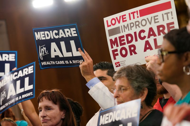 Participants hold signs as Democratic U.S. presidential candidate U.S. Sen. Bernie Sanders (I-VT) speaks at a news conference on Capitol Hill in Washington
