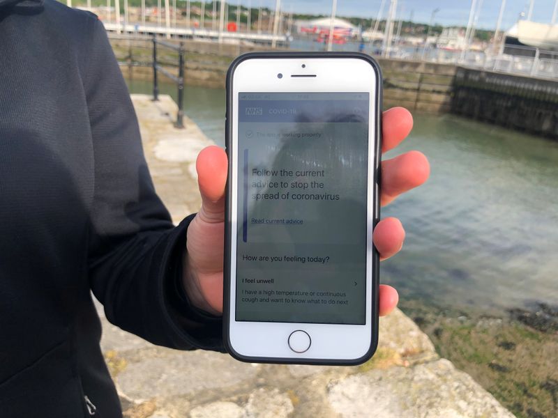 FILE PHOTO: UK National Health Service employee Anni Adams shows a smartphone displaying the new NHS app to trace contacts with people potentially infected with the coronavirus disease (COVID-19) being trialled on Isle of Wight