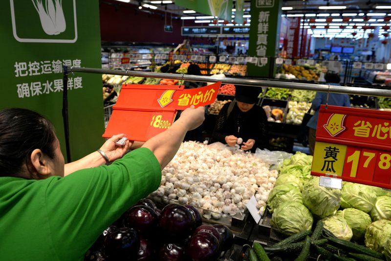 FILE PHOTO: Staff member inserts a price tag for vegetable at a Walmart in Beijing