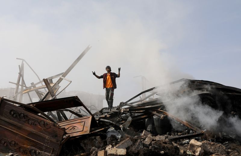 A worker reacts as he stands on the wreckage of a vehicle oil and tires store hit by Saudi-led air strikes in Sanaa