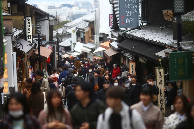 FILE PHOTO: People, wearing protective masks following an outbreak of the coronavirus disease (COVID-19), walk on a street of Gion district in Kyoto