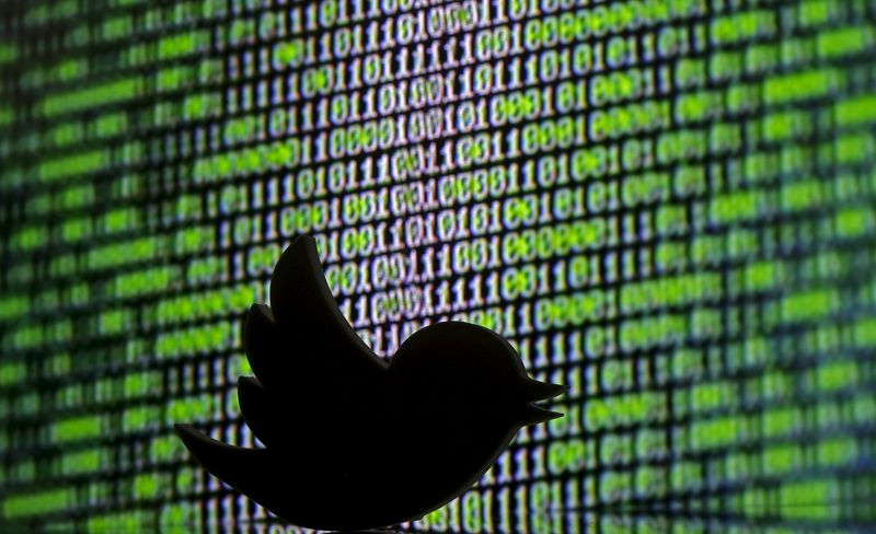 3D printed Twitter logo is seen in front of a displayed cyber code