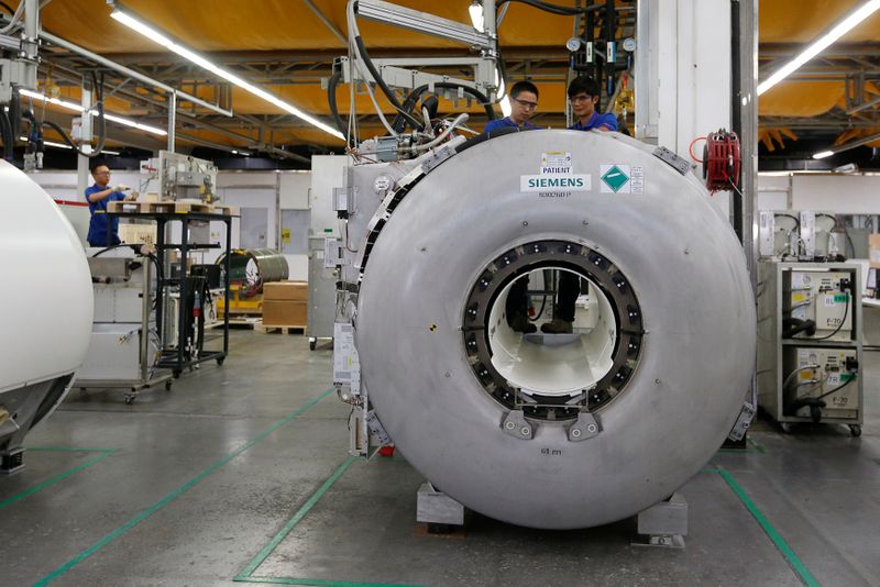 Staff work on magnetic resonance imaging machines at a production line of Siemens Healthineers in Shenzhen