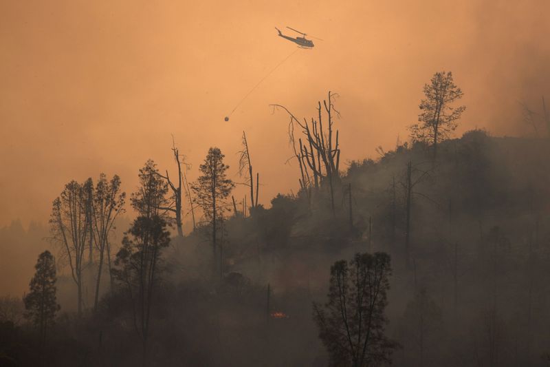 FILE PHOTO: Helicopter releases water on secition of LNU Lightning Complex Fire near Middletown, California