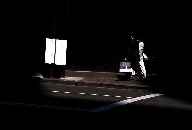 A shopper carries a bag displaying the word 'Sale' as he walks along a footpath outside a retail store in central Sydney
