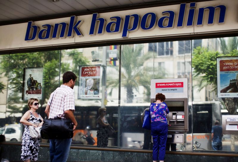 FILE PHOTO: A woman uses an automated teller machine (ATM) outside a Bank Hapoalim branch in Tel Aviv, Israel