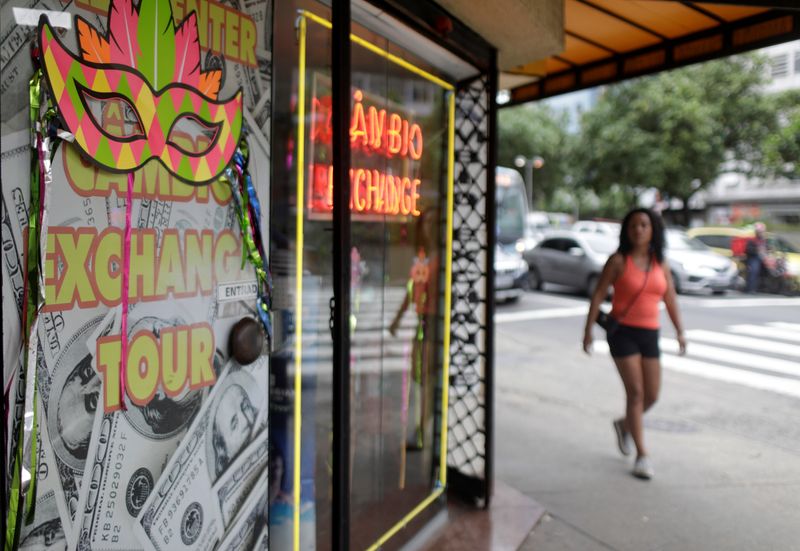 A woman walks past a money exchange office in Rio de Janeiro