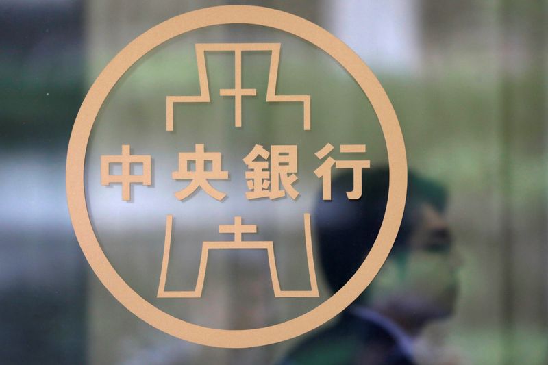 Staff member stands beside the Taiwanese Central Bank logo in Taipei