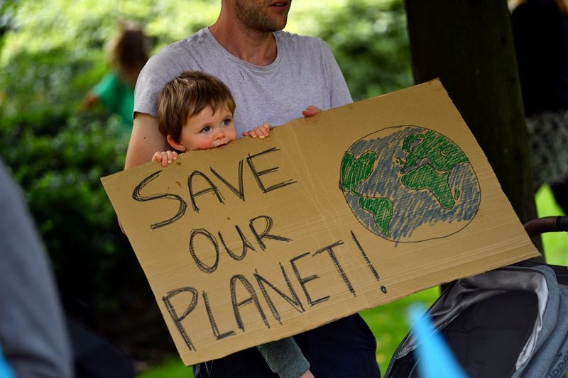 FILE PHOTO: A father and his child are holding a sign as climate activists protest in London