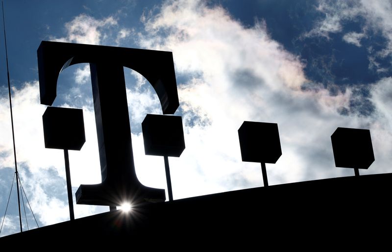 FILE PHOTO: The logo of Deutsche Telekom AG is silhouetted against the sun and clouds atop of the headquarters of German telecommunications giant in Bonn