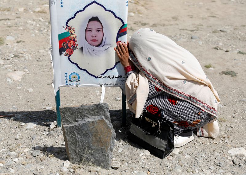 A woman mourns over the grave of her daughter who was killed in a suicide attack in an educational centre two years ago, in Kabul